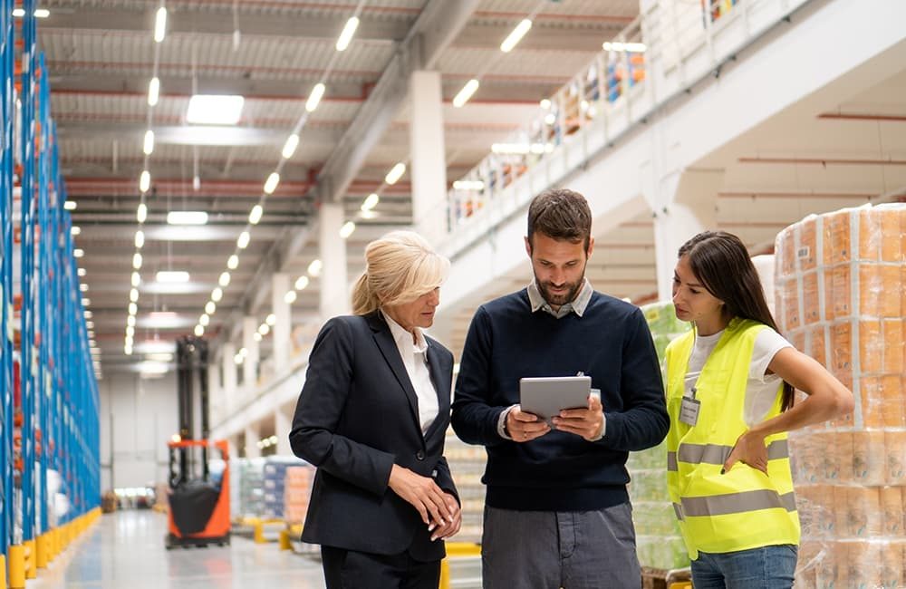 Two women and a man overseeing stock in a warehouse