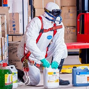 Man in safety suit and bottles of chemicals illustrates PlusChem's expertise in Solvents